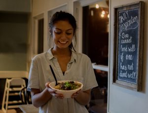 A woman holding a protein bowl from Original ChopShop