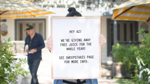 A woman holding a sign promoting Original ChopShops latest loyalty promotion