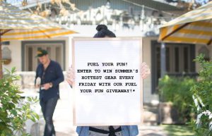 A woman holding a sign showing Original ChopShops latest loyalty Promotion