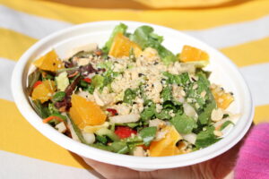 A woman holding a Citrus Thai Salad from Original ChopShop