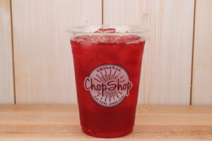 A Hibiscus Mango Iced Tea on a wooden table from Original ChopShop