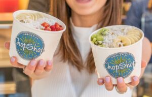 A woman holding a Acai Bowl and a Pitaya Bowl from Original ChopShop