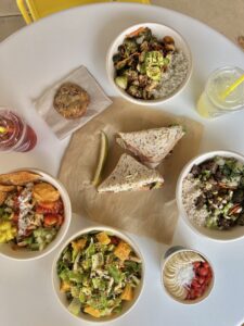 A spread of various Original ChopShop offerings including Sandwiches, Protein Bowls, Salads, and Lemonades